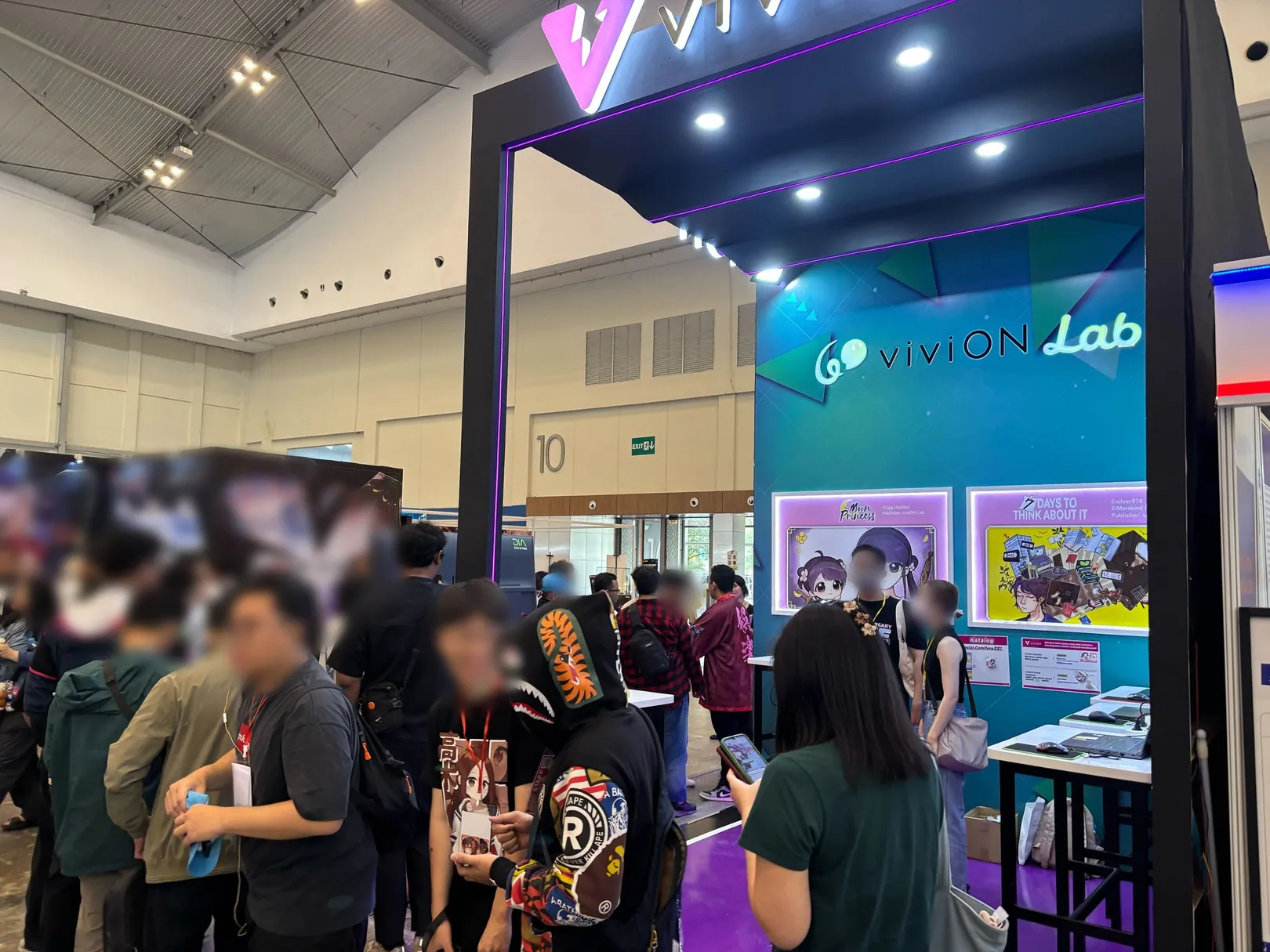 The booth seen from the show floor, with illuminated panels for Moon Princess and another studio's game above the play stations.