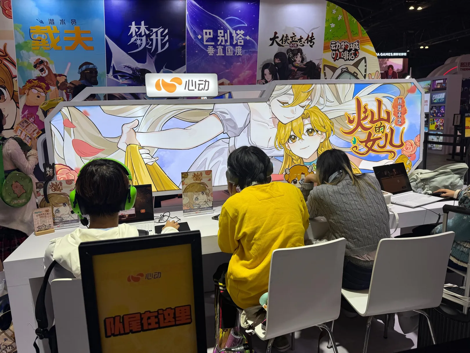 Visitors playing Volcano Princess at a row of laptops, in front of a large illustrated backdrop of the game.